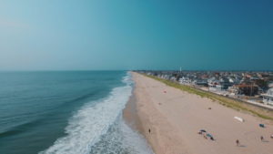 A beach with people laying on it and waves coming in