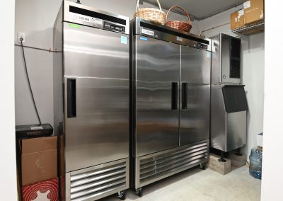 A group of three stainless steel refrigerators in a kitchen.