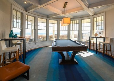 A pool table in the center of a room with windows.