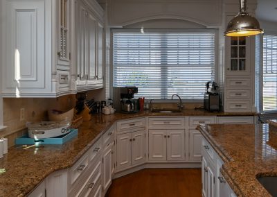 A kitchen with white cabinets and brown countertops.