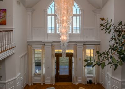 A large chandelier hangs in the center of a foyer.