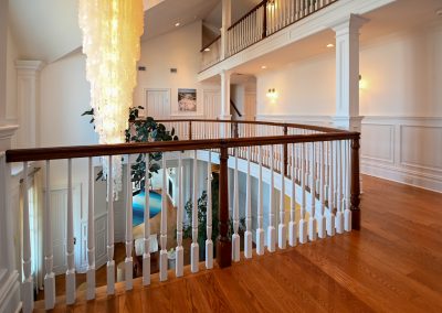 A large open staircase with white railing and wood handrail.